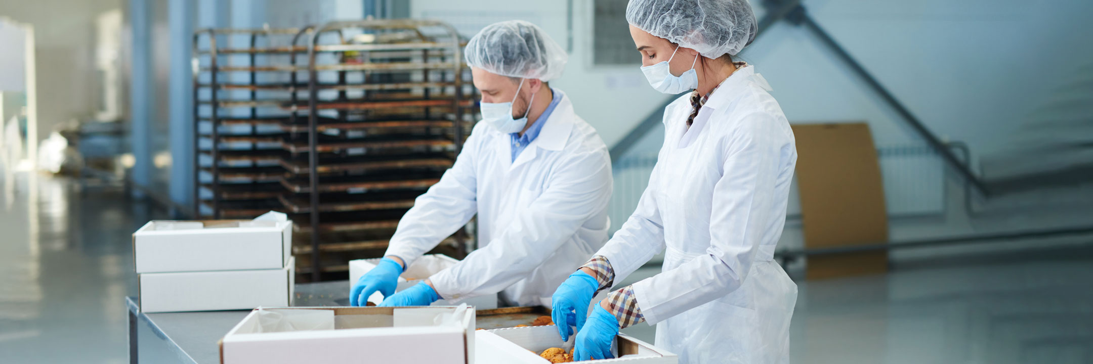 two workers wearing the disposable apparel and packing the things